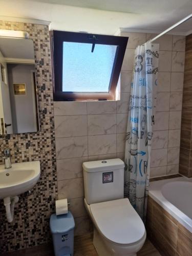 a bathroom with a toilet and a sink and a window at ComeHome in Heraklio Town