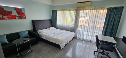 ein Schlafzimmer mit einem Bett, einem Stuhl und einem Schreibtisch in der Unterkunft Oasis Rentals, Diana Estate, Pattaya in Pattaya