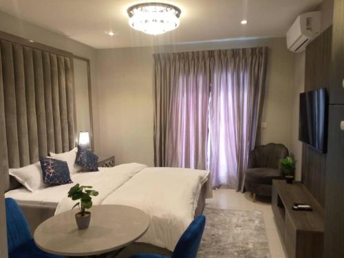 a bedroom with a bed and a table and a tv at The Lennox Luxury Apartment in Accra