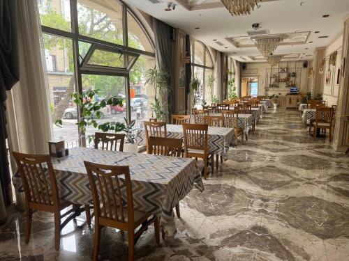 un comedor con mesas, sillas y ventanas en Golden City Hotel Baku en Bakú