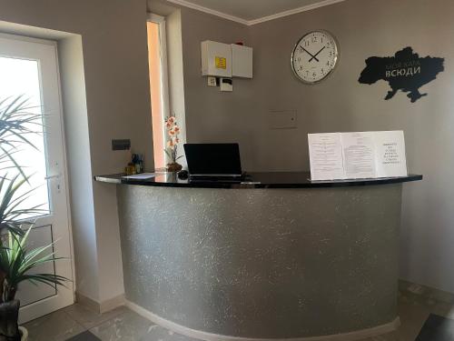 a reception desk with a laptop and a clock on the wall at Готель «У Батька» in Truskavets