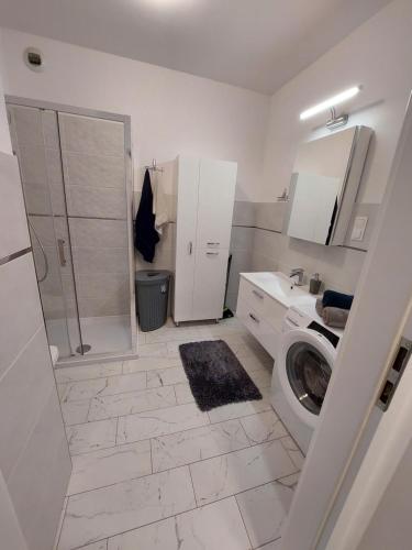 y baño blanco con ducha y lavadora. en Apartament Podpromie en Rzeszów