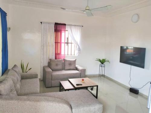 ein Wohnzimmer mit 2 Sofas und einem TV in der Unterkunft Chez Gero in Cotonou