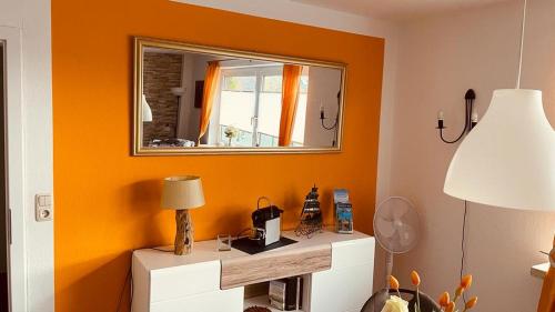 Cette chambre est dotée d'un mur orange et d'un miroir. dans l'établissement Moje Tied, à Emden