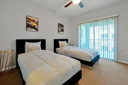 een slaapkamer met 2 bedden en een groot raam bij Loftly Luxury Modern Oasis 2BR 2BA apartment Windermere FL, near Disney, Universal Studios, Magic Kingdom, Pool, Gym, Patio, free cable, wifi, free parking, gym, Alexa, lake, gated community, spacious closets, close to shops and mall in Orlando