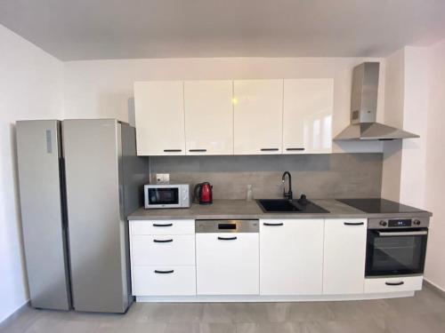 a kitchen with white cabinets and a stainless steel refrigerator at Krasa Escape in Novi Vinodolski