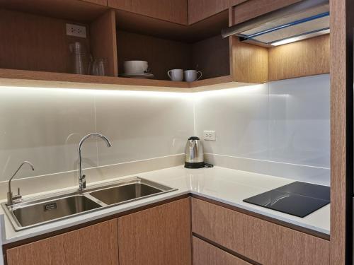 a kitchen with a stainless steel sink and wooden cabinets at Tay Residence in Bangkok