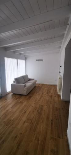 un soggiorno con divano in una camera con pavimenti in legno di Villetta Gest a San Giovanni Rotondo
