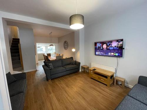 a living room with a couch and a tv on the wall at Hot Tub, Newly refurbished 4 bed, Dog friendly. in Torquay