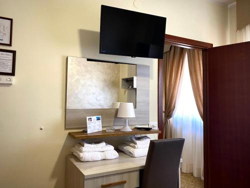 Habitación de hotel con escritorio, TV y toallas. en Hotel Vallisdea en Sala Consilina