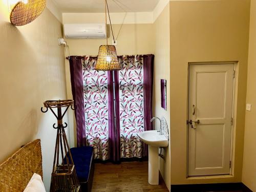 a bathroom with a sink and a door with a window at Paris Guest House in Bharatpur