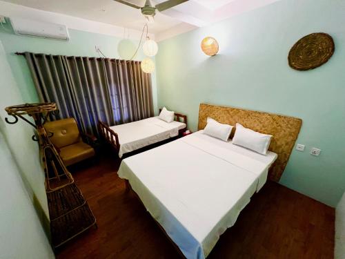 a small bedroom with two beds and a chair at Paris Guest House in Bharatpur