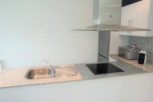 a kitchen counter with a sink and a microwave at LOFT PLAYA BURELA in Burela de Cabo