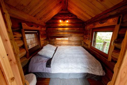 - une chambre dans une cabane en rondins avec un lit dans l'établissement La Cabane des Colibris, à Rieupeyroux