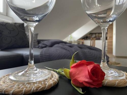 two wine glasses and a red rose on a table at Zeit zum Wohlfühlen FeWo Hofmark 