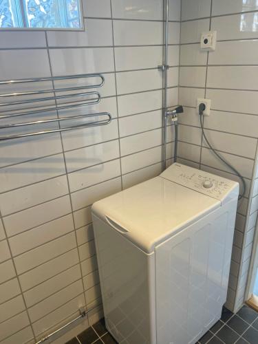 pralka i suszarka w wyłożonej białymi kafelkami łazience w obiekcie Kaptenhuset Skrea strand w mieście Falkenberg