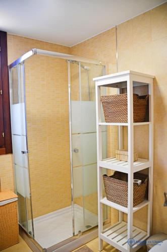 a shower with a glass door and shelves in a bathroom at la cotera vut in Colombres