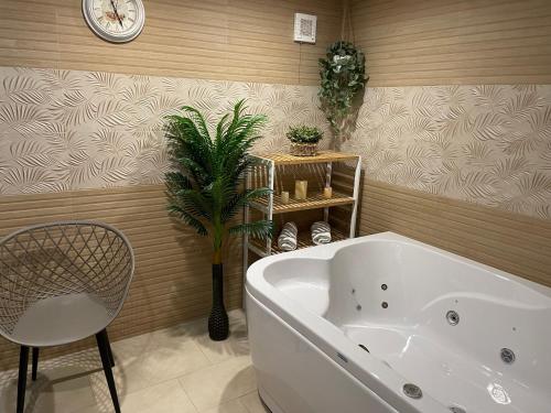 席闊維沙爾克的住宿－Paradise SPA Hotel，带浴缸、植物和时钟的浴室