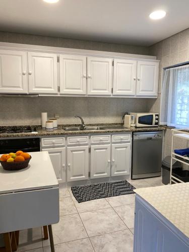 uma cozinha com armários brancos e uma tigela de laranjas no balcão em Casa de Casarelhos - Casa de férias - Gerês em Gerês