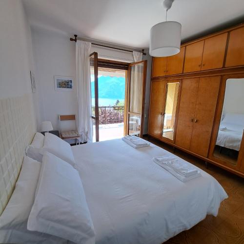a bedroom with a large white bed with a balcony at La casa di Camilla in Perledo
