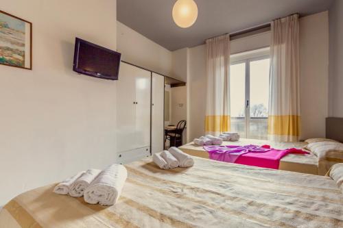 a bedroom with two beds and a tv on the wall at Hotel Airone in Rimini