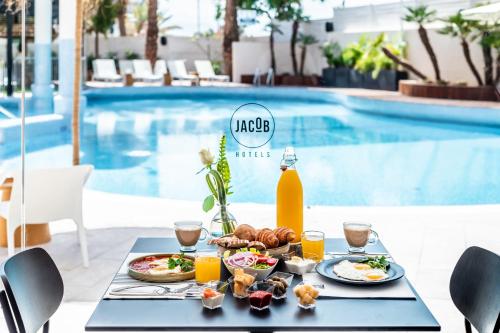 a table with breakfast food on it next to a pool at Jacob Eilat in Eilat