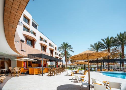 eine Hotelterrasse mit Tischen und Stühlen sowie einem Pool in der Unterkunft Jacob Eilat in Eilat