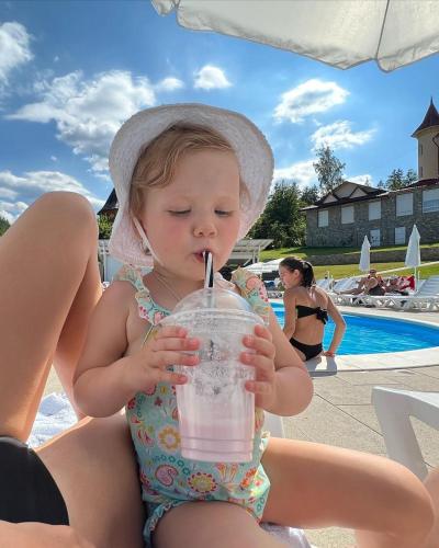 a little girl in a hat drinking a drink at BAYKA - SPA resort in Kosiv