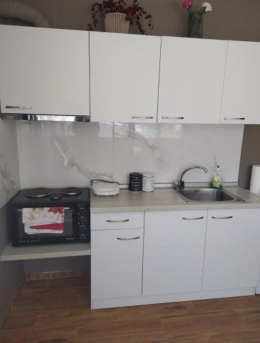 a kitchen with white cabinets and a sink and a microwave at Paradise of Meteora A in Kastrákion