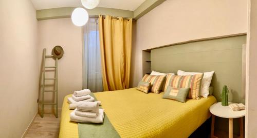 a bedroom with a yellow bed with towels on it at Street View in La Morra
