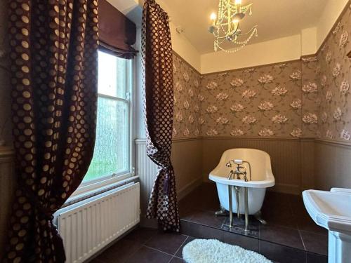 uma casa de banho com uma banheira, um lavatório e uma janela em Annsborough House Castlewellan em Castlewellan