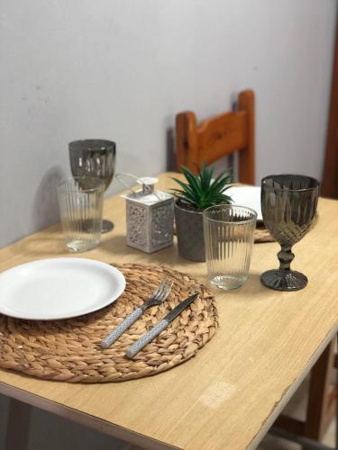 a wooden table with a plate and glasses on it at The 3 Little Pigs apartments in Sidari