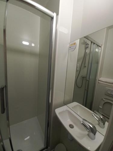 uma casa de banho com um lavatório e um chuveiro com um espelho. em Premiere Classe Evry Sud - Mennecy em Ormoy