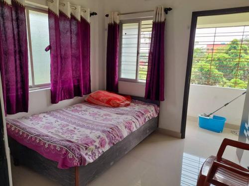 a small bedroom with purple curtains and a bed at Debjit Residency for Family only in Kolkata