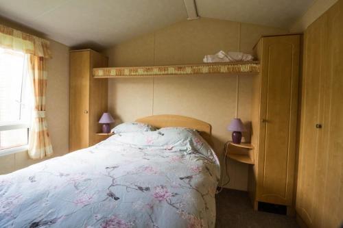 1 dormitorio con 1 cama y 2 lámparas en un estante en Lovely 6 Berth Caravan At Naze Marine Holiday Park In Essex Ref 17003c, en Walton-on-the-Naze