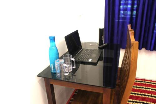 a glass table with a laptop and glasses on it at Arabian Nights Munnar Pool Villa in Munnar