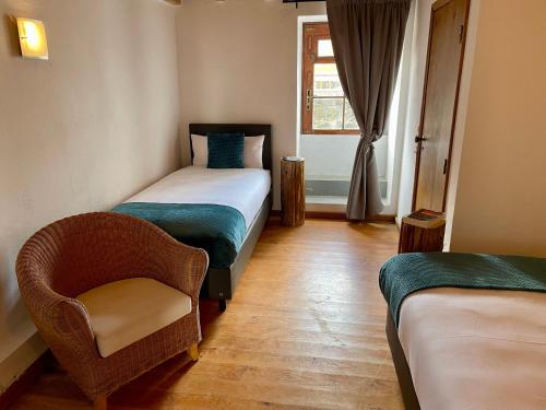 a bedroom with a bed and a chair and a window at Pátio Ecolodge in Cedros