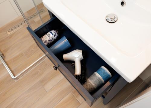 a drawer under a sink with a roll of toilet paper at Wakacyjny Rewal / Dookoła Świata in Rewal