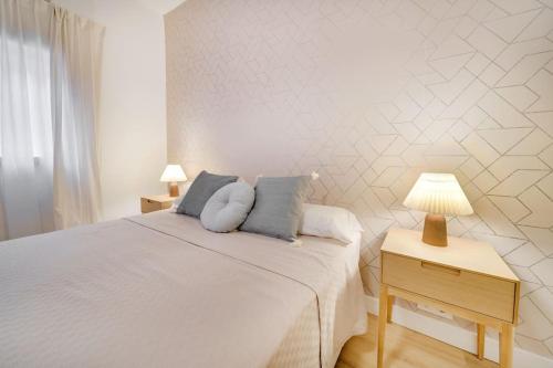 a white bedroom with a bed and a table with a lamp at Esplendido apartamento en el centro in Málaga