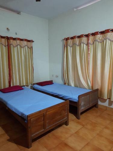 2 camas en una habitación con cortinas en Nandanam homestay en Varkala