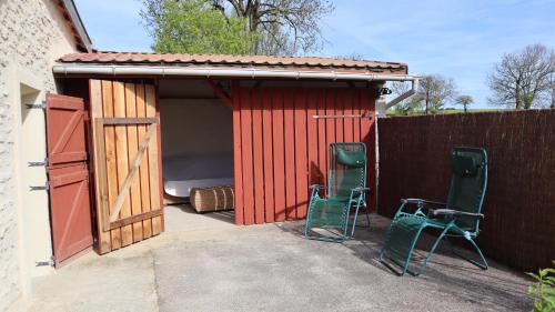 a red shed with two chairs and a bed in it at Le Val Sambon in Dampierre-en-Montagne