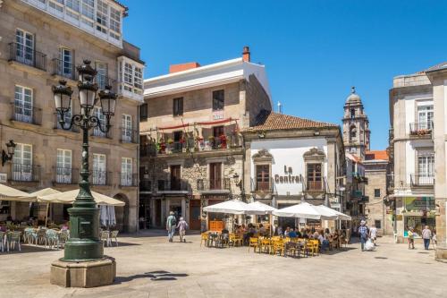 uma praça da cidade com mesas, cadeiras e edifícios em Apartamento vacacional en Playa del Vao - Corujo em Vigo