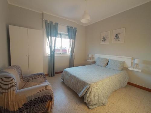 a bedroom with a bed and a chair in it at Apartamento vacacional en Playa del Vao - Corujo in Vigo