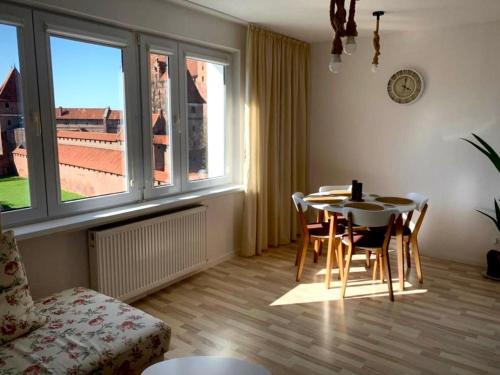 a living room with a table and chairs and a window at Widok Zamku o poranku in Malbork