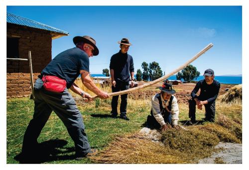a group of men standing around a man holding a stick at titicaca lodge - LUQUINA in Luquina