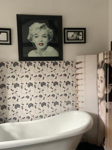 uma casa de banho com banheira e uma fotografia de uma mulher em Tathan Herd em Flemingston