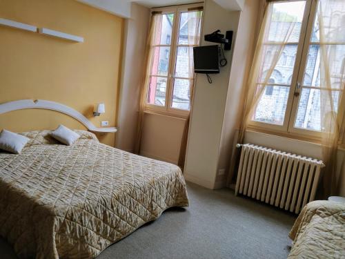 een slaapkamer met een bed, een tv en ramen bij Hôtel restaurant Notre Dame in Orcival