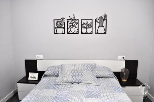 ログローニョにあるMúgica - Gran Víaのベッドルーム1室(壁に4つの植物が飾られたベッド1台付)