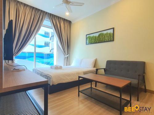 a bedroom with a bed and a couch and a window at The Wave Suites Melaka by BEESTAY in Melaka