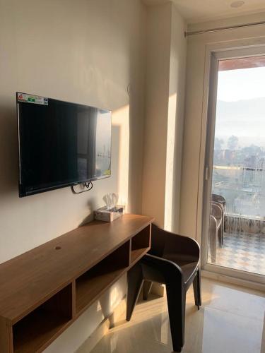 a room with a desk with a television on a wall at Nature's Blessing Rishikesh 1BHK Studio in Rishīkesh